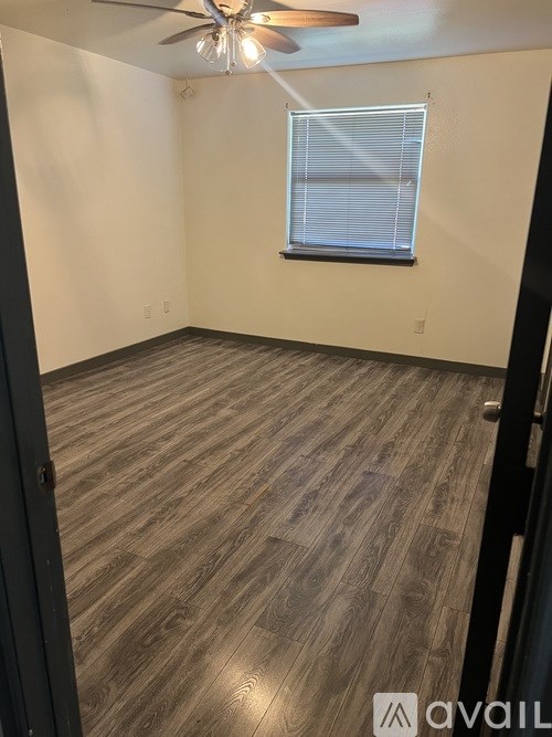 A room with a ceiling fan and wooden flooring.