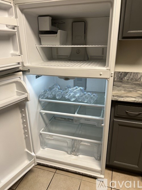 A white refrigerator with the door open and ice trays inside.
