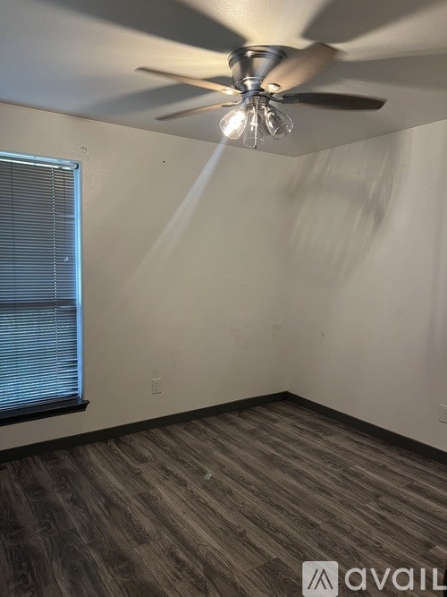 A room with a ceiling fan and a window with blinds.