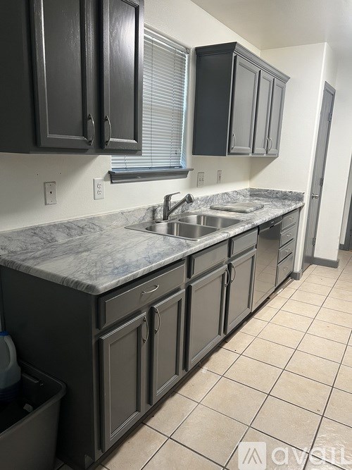A kitchen with black cabinets and a marble countertop.