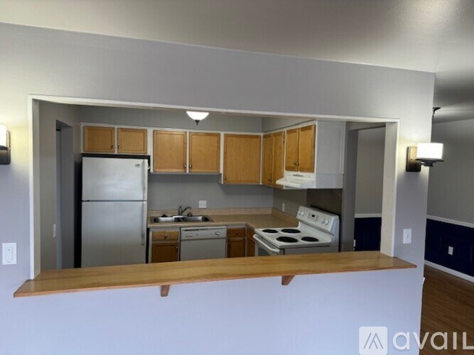 A kitchen with a refrigerator, stove, and cabinets.