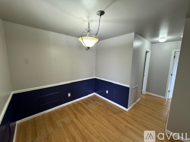 A room with a wooden floor and a chandelier hanging from the ceiling.