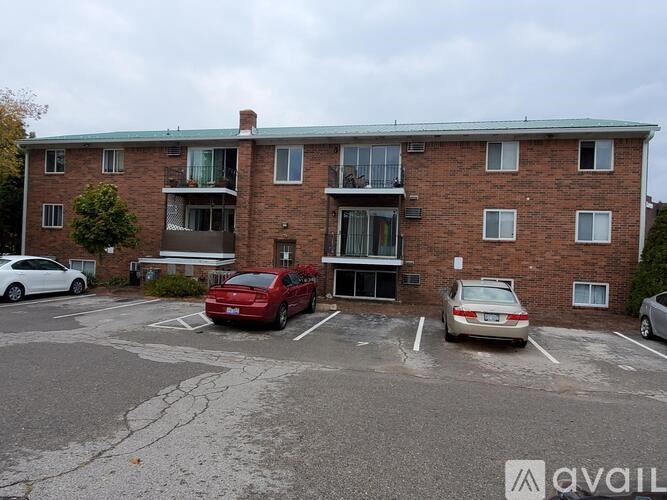 A parking lot in front of a brick apartment building with cars parked.