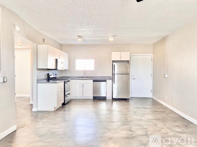 A kitchen with white cabinets and a stainless steel refrigerator.