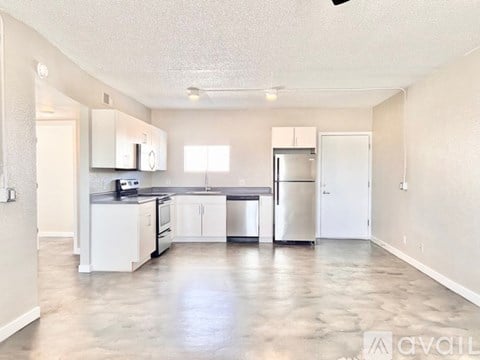 A kitchen with white cabinets and a stainless steel refrigerator.