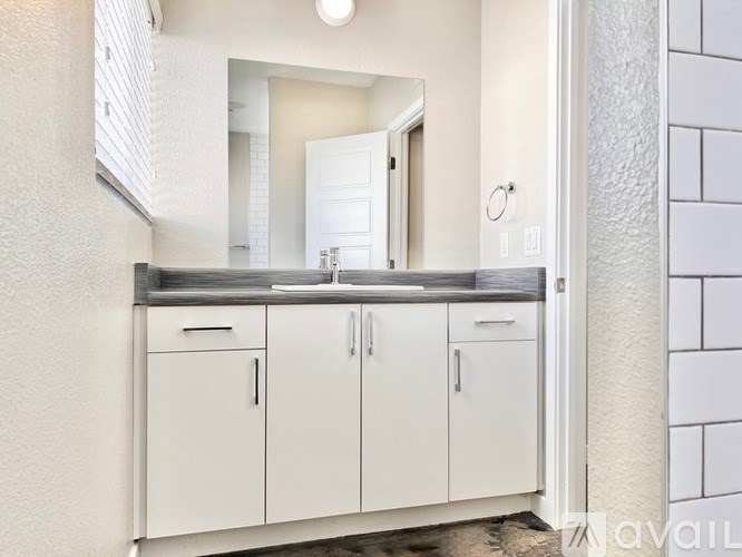 A bathroom with a sink, mirror, and cabinets.