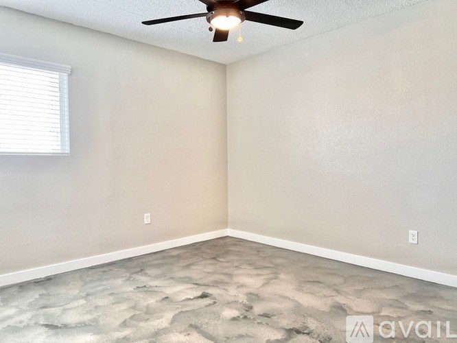 A room with a ceiling fan and a window with blinds.