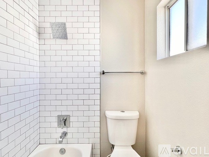 A white toilet sits next to a white sink in a bathroom with white tiles.