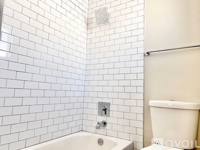 A white tiled bathroom with a shower, sink, and toilet.
