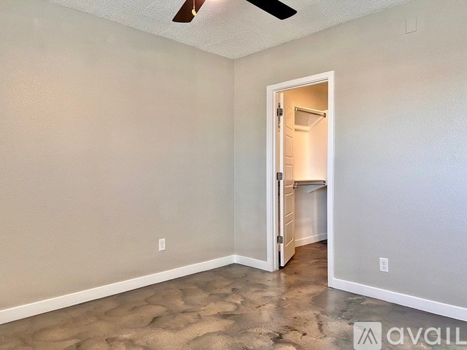 A room with a ceiling fan and a doorway leading to another room.
