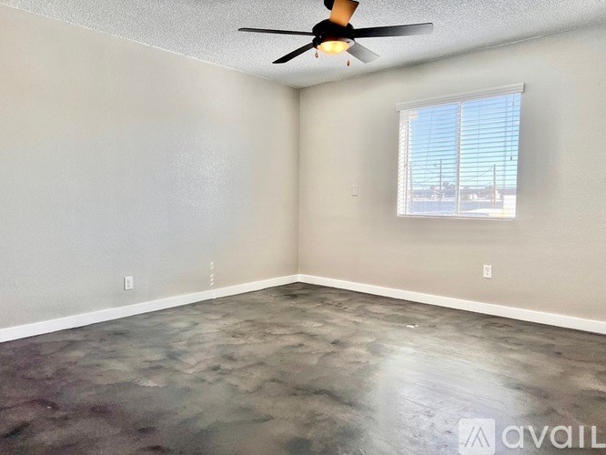 A room with a ceiling fan and a window with blinds.