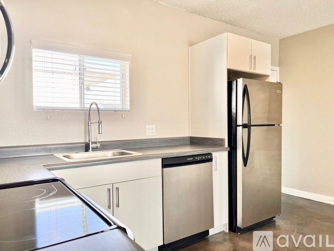 A kitchen with a stainless steel refrigerator and a stainless steel sink.