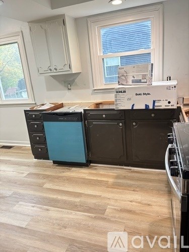 A kitchen with a black dishwasher and a blue dishwasher cabinet.