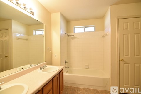 A bathroom with a white tub, sink, and mirror.