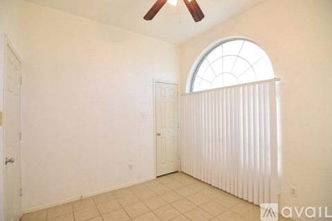 A room with a ceiling fan and a window with blinds.