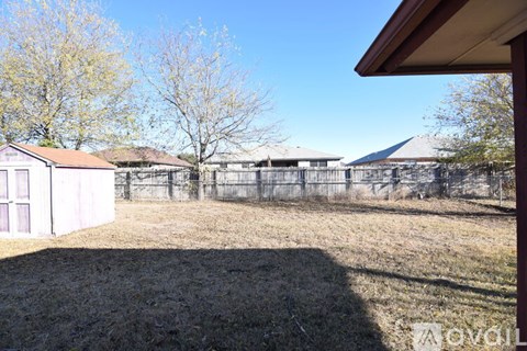 A backyard with a fence and a shed.
