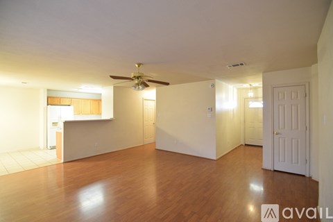 A spacious room with wooden floors and a ceiling fan.