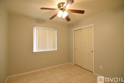 A room with a ceiling fan and a window with blinds.
