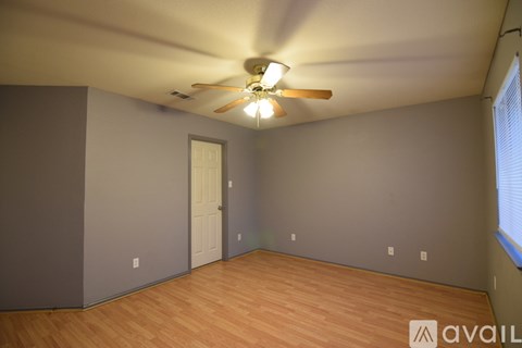 A room with a ceiling fan and wooden flooring.