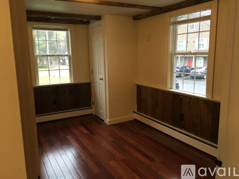 A room with wooden floors and two windows.