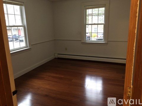 A room with wooden floors and two windows.