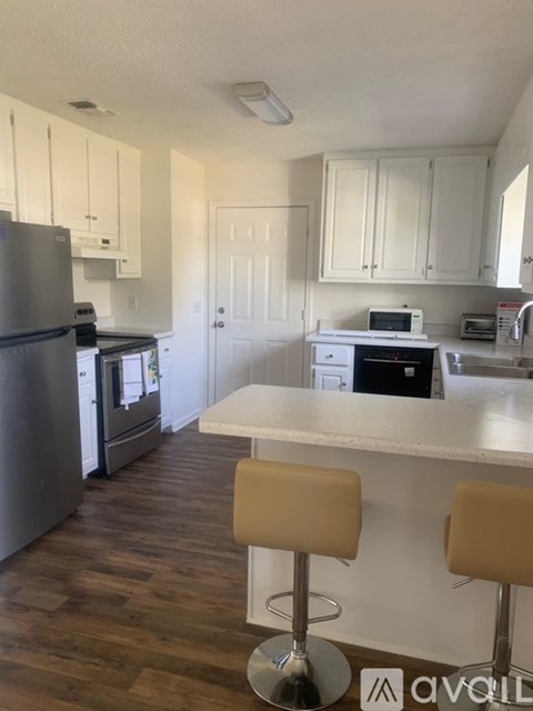 A kitchen with white cabinets and a wooden floor.