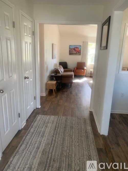 A hallway with a rug on the floor and a painting on the wall.
