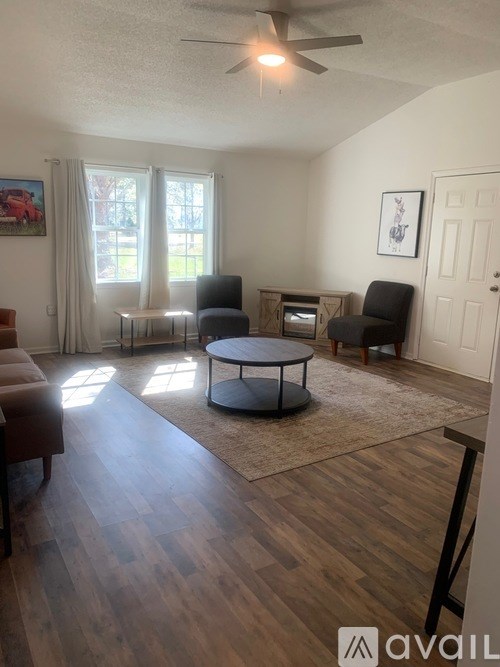 A living room with a brown sofa, a black chair, and a round table.