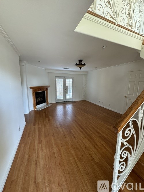 A room with wooden floors and a staircase with a decorative railing.