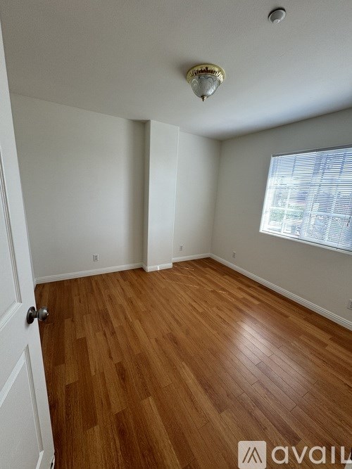 A room with wooden flooring and a window with blinds.