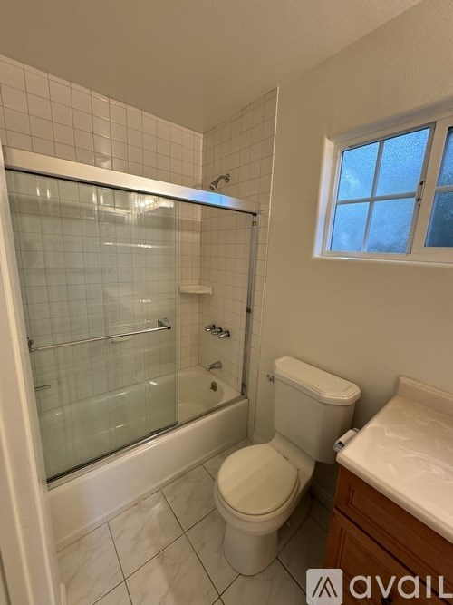 A bathroom with a toilet, a glass shower stall, and a window.