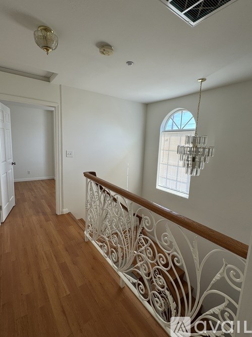 A living room with a chandelier, a window, and a staircase.