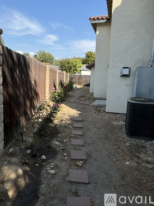A backyard with a wooden fence and a brick pathway.