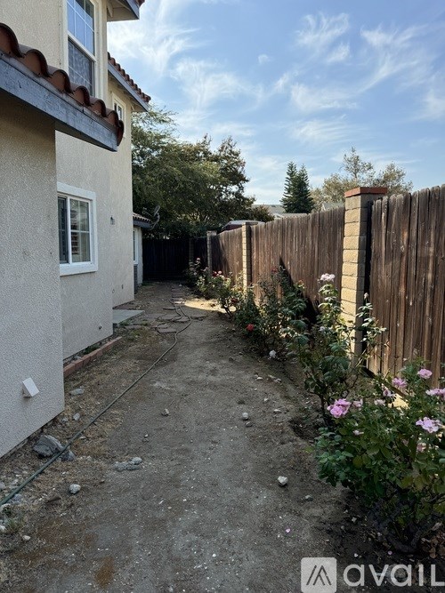 A narrow alley with a wooden fence and some flowers on the side.