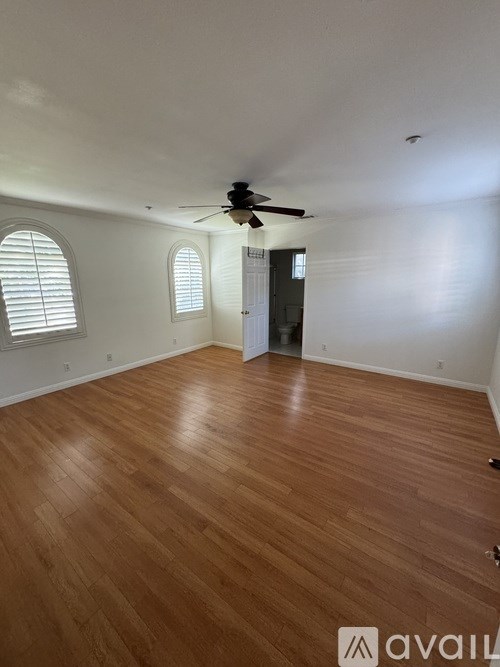 A room with wooden flooring and a ceiling fan.