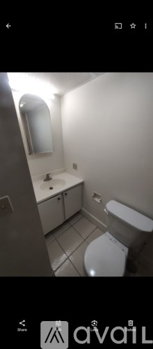 A white toilet in a small bathroom with a sink and mirror.