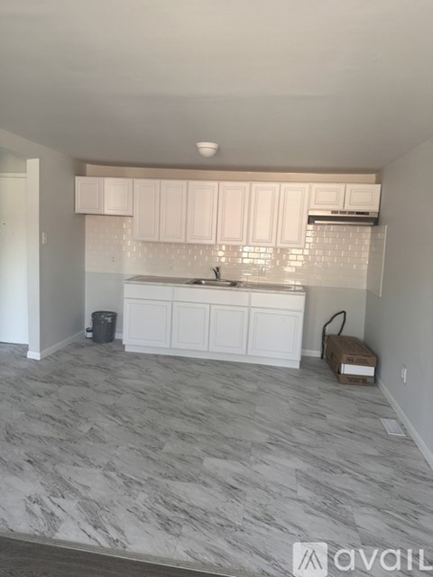 A kitchen with white cabinets and a marble floor.