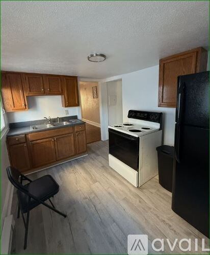 A kitchen with wooden cabinets and a black chair.