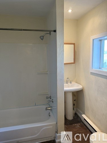 A white bathroom with a tub, sink and mirror.