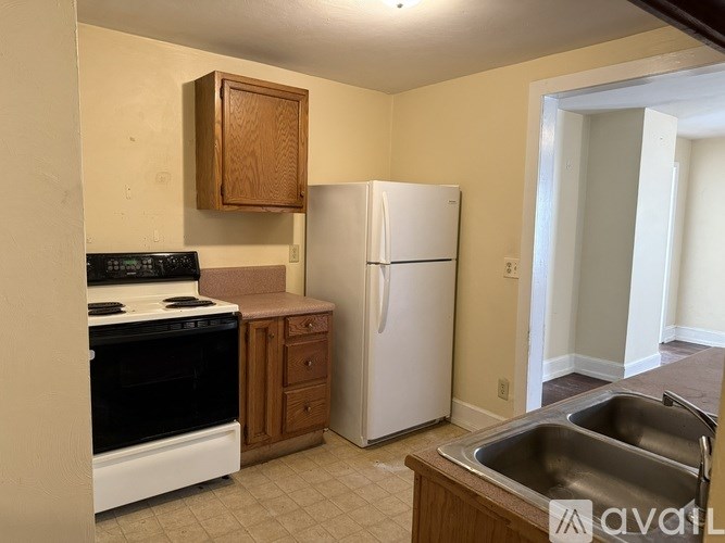 A kitchen with a white refrigerator, black stove, and wooden cabinets.