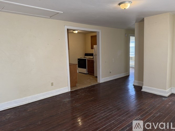 A room with wooden floors and a doorway leading to another room.