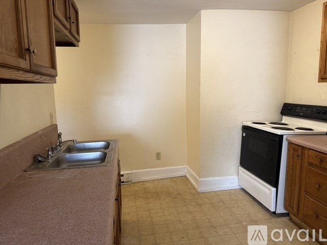 A kitchen with a sink, stove, and cabinets.