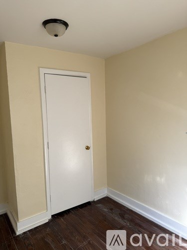 A white door is in a room with wooden floors and beige walls.