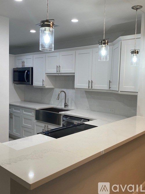 A modern kitchen with white cabinets and a marble countertop.