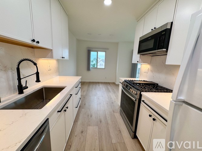 A kitchen with white cabinets and a marble countertop.