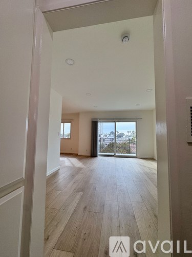A room with wooden floors and a sliding glass door leading to a balcony.