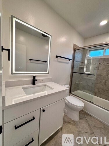 A bathroom with a sink, mirror, toilet and shower.