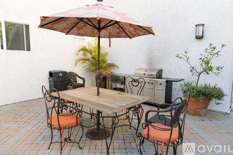 A table with chairs and an umbrella is set up on a patio.