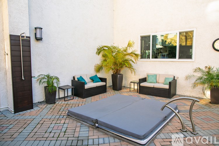 A patio with a couch, chair, and potted plants.