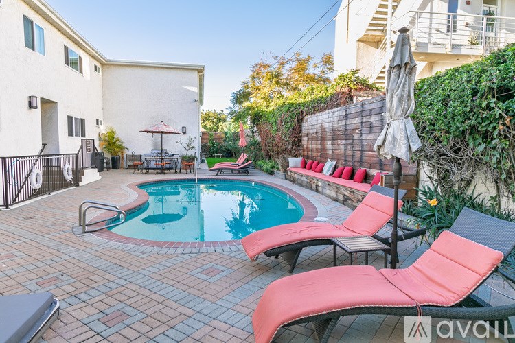 A pool surrounded by red chairs and a black fence.